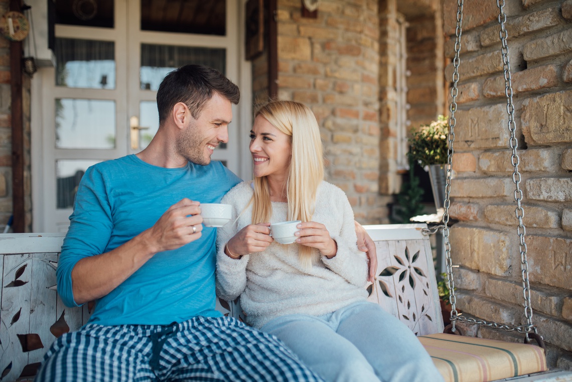 Portrait picture of Happy couple drinking tea while sitting on the balcony