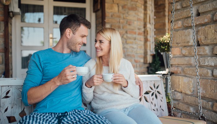 Happy couple drinking tea while sitting on the balcony